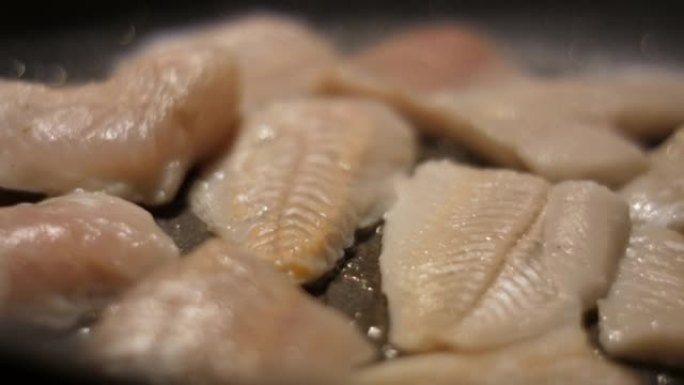 用油关闭煎锅的鱼片带鱼。烤健康食品。油炸鳕鱼片配香料特写。健康饮食欧米茄3。低热量白肉。
