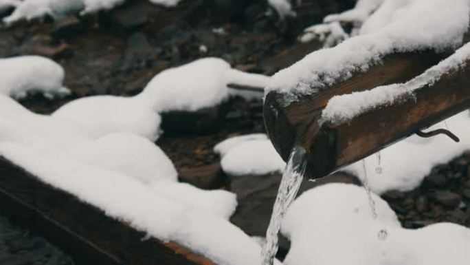 大雪清洁，透明的山水流从木制排水沟流入特殊槽