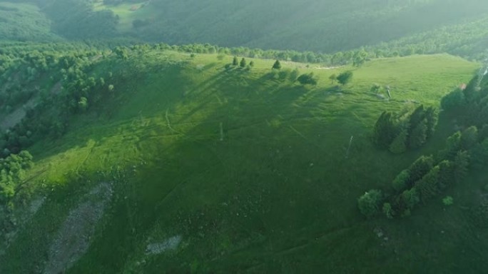 从无人机上可以看到美丽的山景。无人机飞越森林和群山之间的绿色草地。美丽的阳光照在山上，阴云密布。