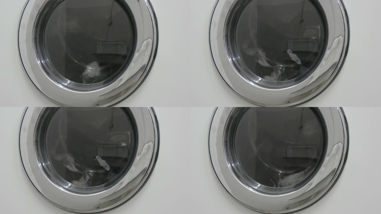黑白衣服。衣物在洗衣店的白色洗衣机中洗涤。