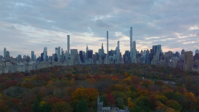 中央公园周围摩天大楼的全景。向后揭示秋季彩树之间的旅游景点。美国纽约市曼哈顿