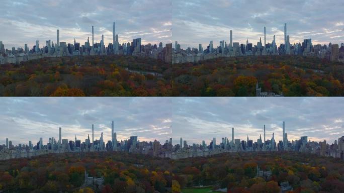 中央公园周围摩天大楼的全景。向后揭示秋季彩树之间的旅游景点。美国纽约市曼哈顿