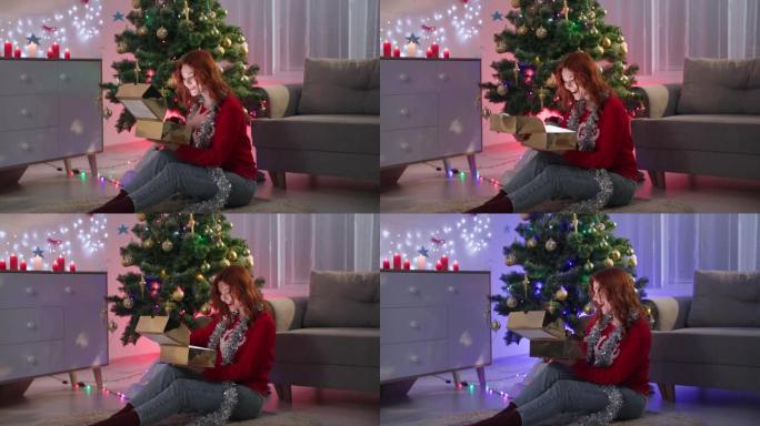 新年礼物，穿着红色毛衣的快乐年轻美女在晚上打开盒子，光线照在她的脸上，背景为带有花环的圣诞树