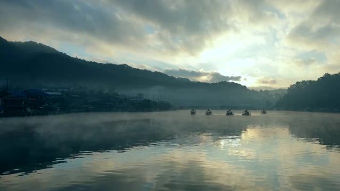 在早晨的阳光下在山湖上移动雾，船在自然中航行
