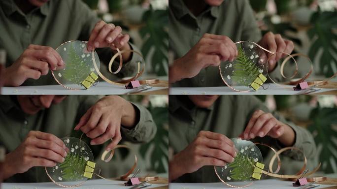 女人修理玻璃板。干花的照片。蒂芙尼技术在彩色玻璃中使用植物标本室创建框架的大师班