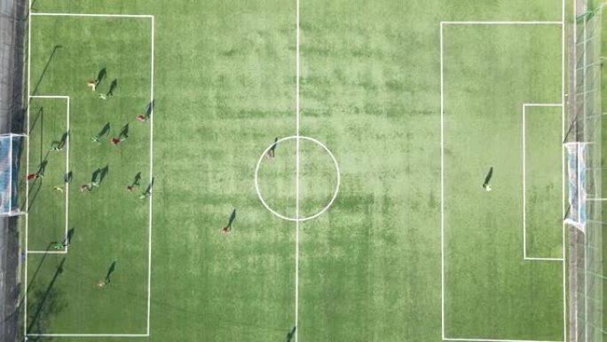 在绿色体育馆踢足球的足球运动员的鸟瞰图