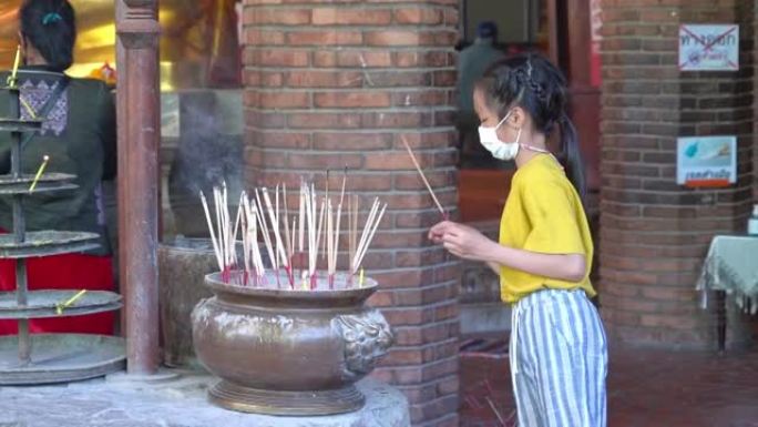泰国小女孩正在泰国寺庙点燃佛香，用于拜佛。