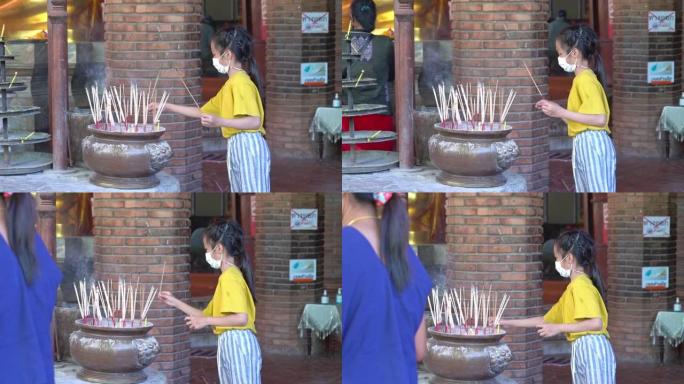 泰国小女孩正在泰国寺庙点燃佛香，用于拜佛。