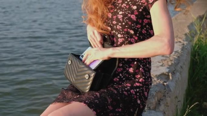 女性将时尚智能手机放入黑色时尚手提包中