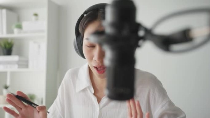 年轻的亚洲女性在家庭工作室的笔记本电脑上录制播客。