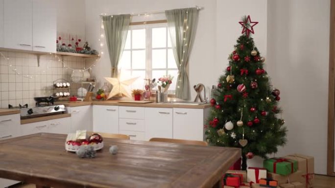 圣诞房间内部。舒适的烹饪场所由圣诞树装饰，明亮的窗户在餐桌上摆放着五颜六色的礼物。美丽的公寓为新年假