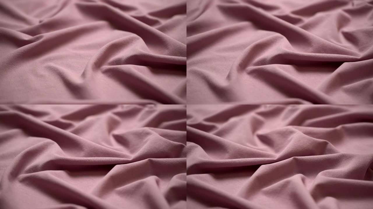 织物布背景。纹理棉纺织材料特写。裁缝桌上的粉红色波浪状褶皱织物