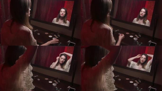迷人的白人年轻女子穿着睡袍在卧室的镜子前梳头。使女人的外表井然有序