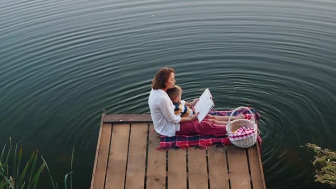 妈妈的俯视图在湖上给小儿子读书