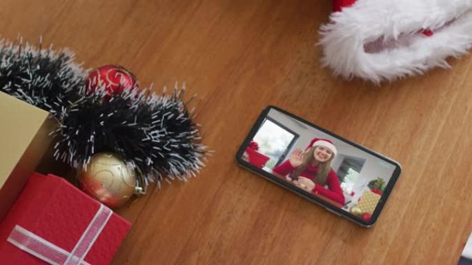 微笑的白人妇女在智能手机上的圣诞节视频通话中戴着圣诞老人的帽子