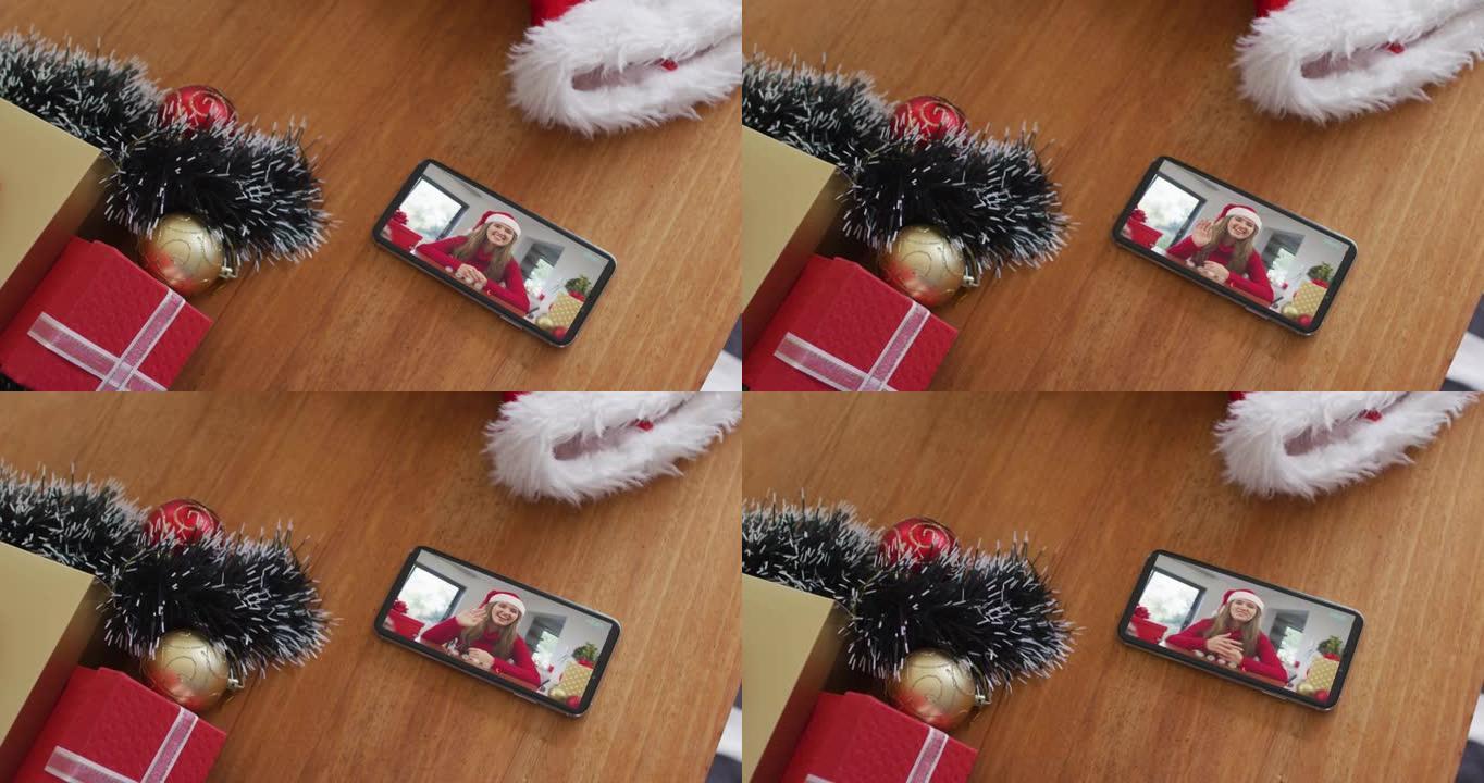 微笑的白人妇女在智能手机上的圣诞节视频通话中戴着圣诞老人的帽子