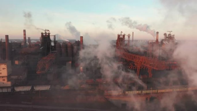 无人机围绕有毒的企业烟囱管道在天空背景下释放烟雾。工厂污染环境。鸟瞰图