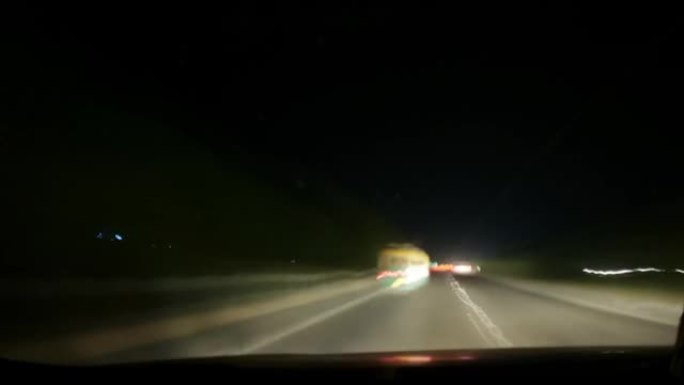 从车内挡风玻璃脏的情况下，夜间高速公路的4k过度行驶。车内的视点。汽车离开小路。旅游背景。汽车夜间高