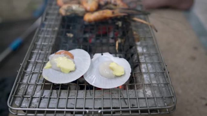 涂黄油的扇贝在高热的木炭烤架上烤，等待煮熟后才能食用。