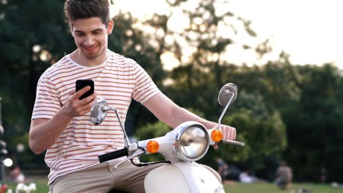 快乐男人在户外滑板车上使用手机