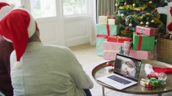 多元化的资深女性朋友使用笔记本电脑进行圣诞节视频通话，屏幕上有微笑的男孩