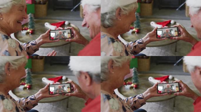 高级高加索夫妇使用智能手机与屏幕上的快乐男人进行圣诞节视频通话