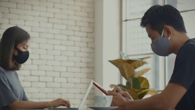 新型冠状病毒肺炎效果，在家工作，忙碌的亚洲年轻夫妇使用笔记本电脑和智能手机。家庭生活，影响新型冠状病