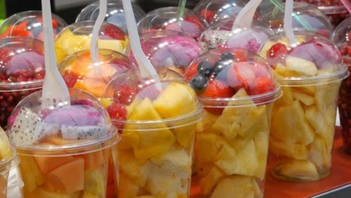 柜台上有热带水果，芒果，百香果，猕猴桃，香蕉，草莓塑料包装。健康的新鲜饮食食品随时可以食用，各种切成