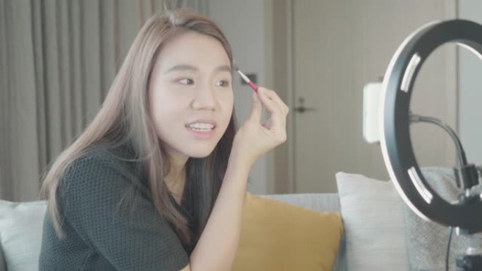 特写亚洲女性博主在家在线影响者录制化妆化妆品视频。