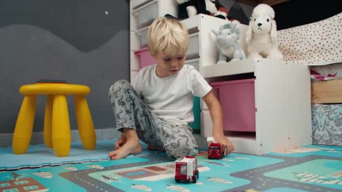 可爱的小男孩在家里的儿童卧室里玩玩具救火车