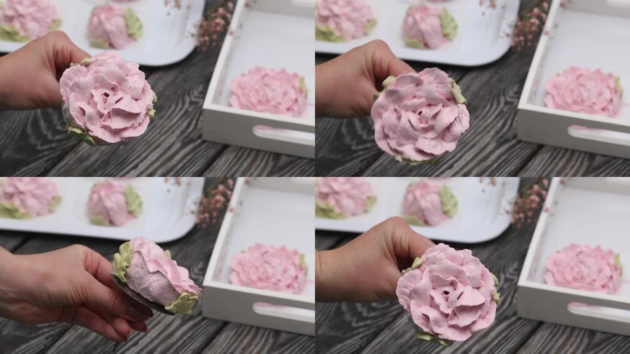 一个女人手里拿着由棉花糖制成的花。让西风玫瑰站在架子上。在黑色松木板的背景下。特写镜头。