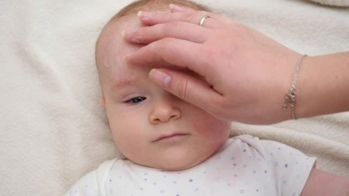 母亲涂霜保湿和清洁婴儿面部的特写镜头。新生婴儿卫生、健康和皮肤护理的概念