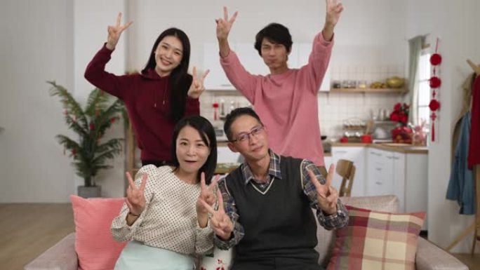 中国春节期间，兴高采烈的父亲、母亲、成年女儿和儿子看着相机，做着胜利的拇指手势，在家里连续拍摄