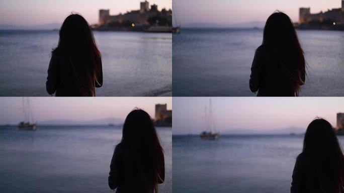 站在外面的海上看日落的美丽女孩