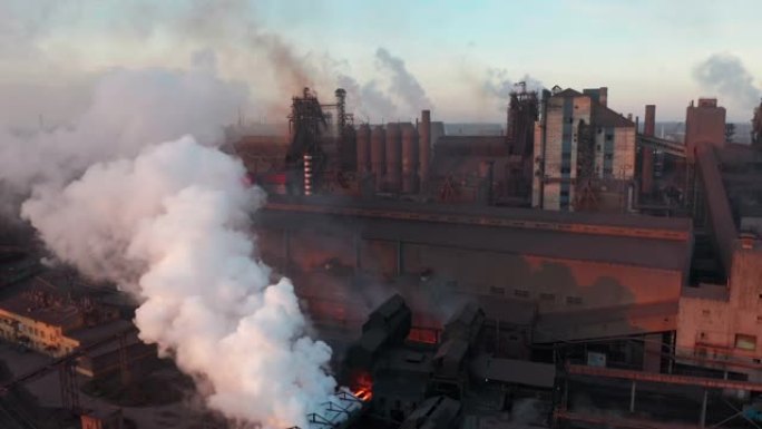 无人机围绕有毒的企业烟囱管道在天空背景下释放烟雾。工厂污染环境。鸟瞰图