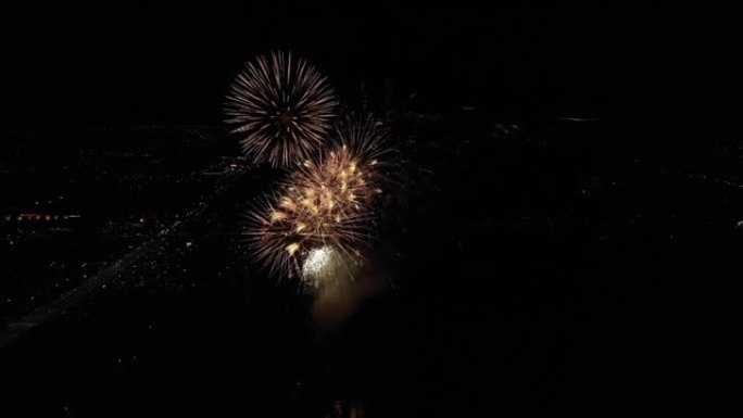 黄金烟花的无人机视频在夜间在城市上空高空爆炸