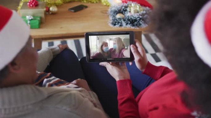非裔美国母亲和女儿使用平板电脑与屏幕上的家人进行圣诞节视频通话