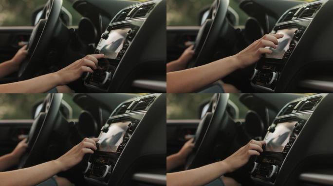 一名年轻女子坐在驾驶座上。她正在汽车多媒体中选择音乐。她正在使用触摸屏。她的手特写。4K 50fps