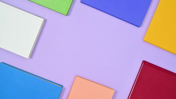 不同鲜艳颜色的精装书框架在紫色主题上移动。停止运动
