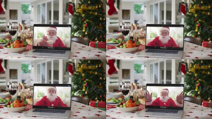 快乐的高加索圣诞老人躺在圣诞桌上的笔记本电脑上