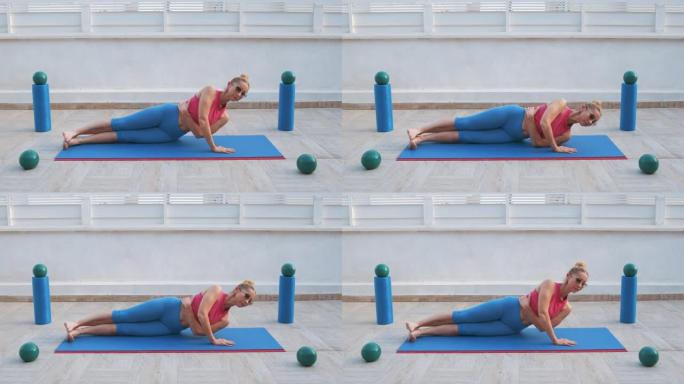 健身女子在运动垫上做腹肌侧嘎吱的手放在木板位置