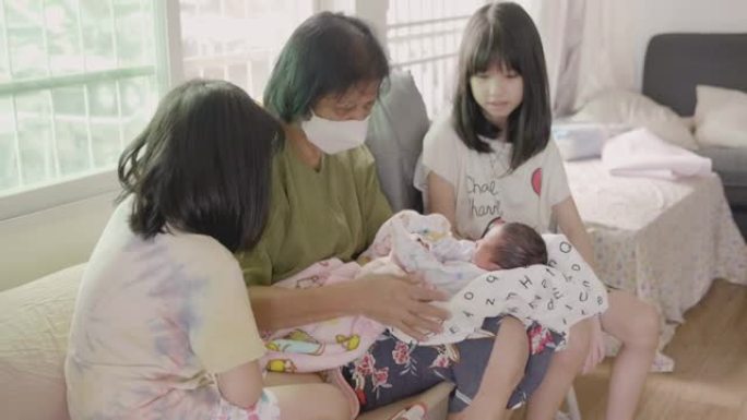祖母抱着的亚洲宝贝新生儿和妹妹照顾他。