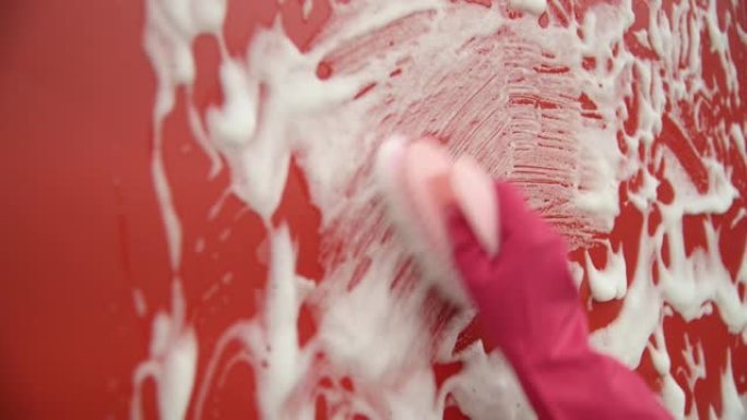 女人用刷子手清洁红墙