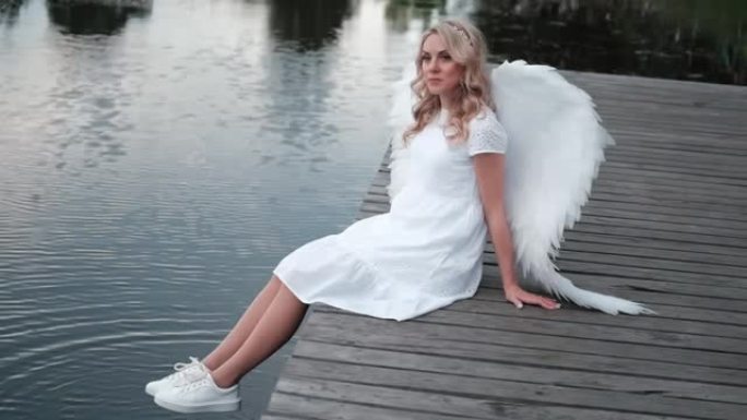 有白色天使翅膀的女人。穿着天使服装的美丽金发女郎。天堂，纯洁。好人。慢动作