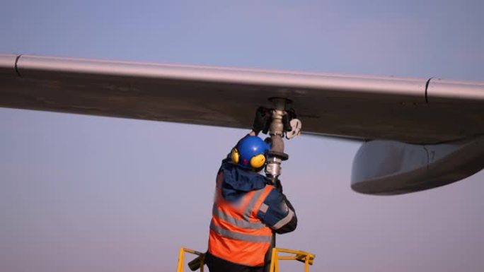 机场飞机机组人员由技术人员维护地面为航空公司的飞机加油。准备飞机起飞，维修飞机服务人员在飞机机翼，楼