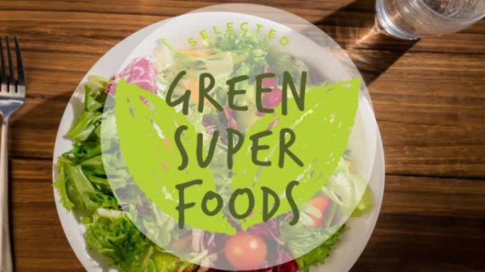 绿色超级食品文本的动画在木桌上的新鲜沙拉盘子上