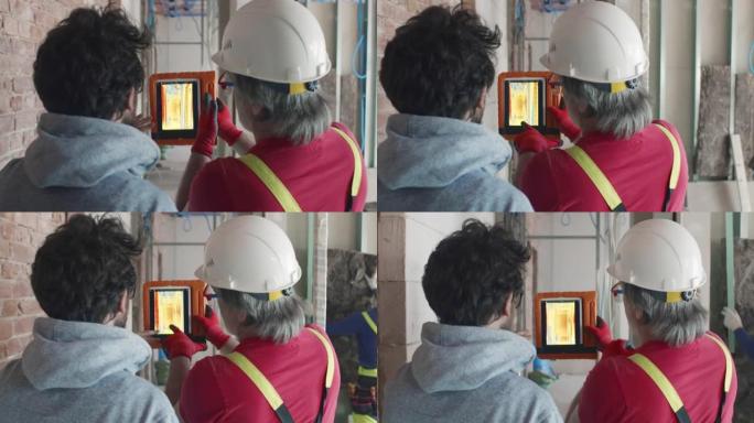 承包商和建筑商的后视图在施工现场使用红外摄像机。实时
