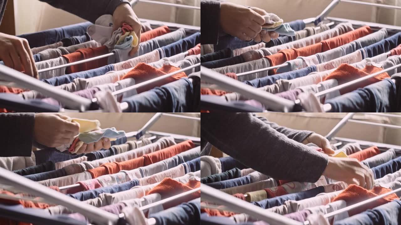 手把湿的婴儿衣服放在家里晾干，特写。