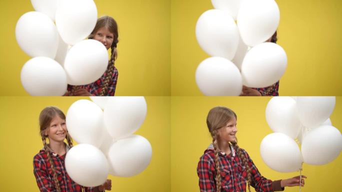 白色气球与迷人的十几岁的高加索女孩出现在黄色背景微笑。积极美丽苗条的少年慢动作摆姿势。幸福和快乐概念