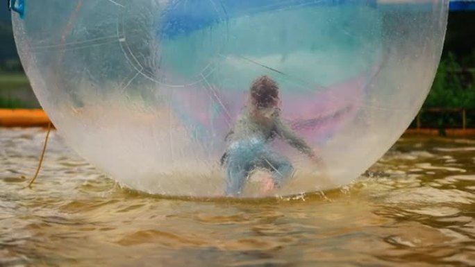 小女孩在池塘里的大水球里爬行很开心
